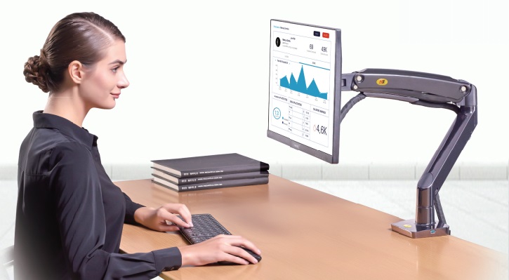 Trong hìn là cô gái đang ngồi bên chiêc khung treo màn hình máy tính 24 inch dạng khớp được lắp đặt hoàn thiện trên bàn làm việc