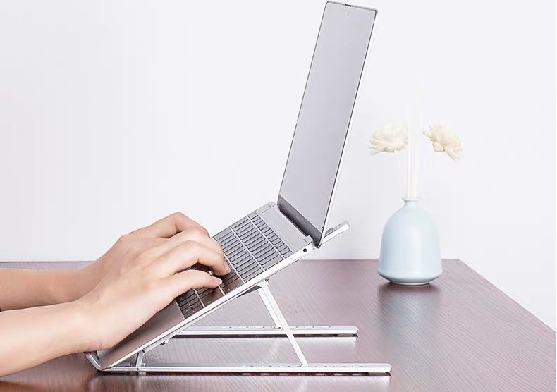 Giá đỡ laptop đang đặt trên bàn hỗ trợ việc gõ bàn phím thuận tiện hơn