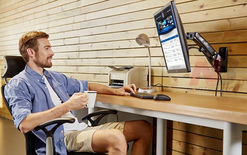 Trong hình là người đang ngồi làm việc cùng máy tính được gắn lên chiếc giá đỡ màn hình 19 inch gắn tường
